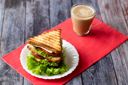 Sandwich with cheese, tomato, cucumber, sausage and salad on wooden background. Coffee with milk Horizontal orientationの写真素材