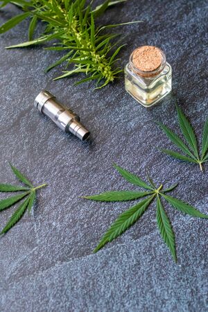 Close-up Vaping Cannabis THC Oil Extract in Cartridge Isolated on Dark Background with Marijuanaの写真素材