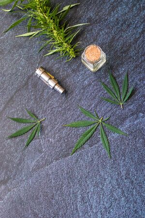 Close-up Vaping Cannabis THC Oil Extract in Cartridge Isolated on Dark Background with Marijuanaの写真素材