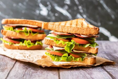 Sandwich with cheese, tomato, cucumber, sausage and salad on wooden background. Horizontal orientationの写真素材