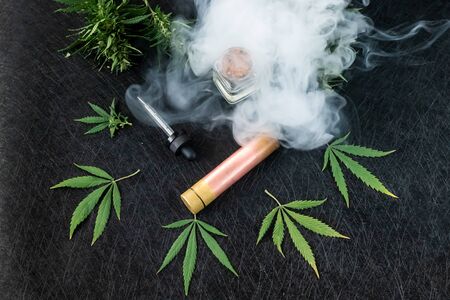 Cannabis liquid. Vape CBD or THC, Vaping Marijuana and Hemp. Against a Dark Background. Thick steam. Horizontal orientationの写真素材