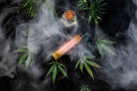 Cannabis liquid. Vape CBD or THC, Vaping Marijuana and Hemp. Against a Dark Background. Thick steam. Horizontal orientationの写真素材