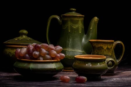 A bunch of grapes in an old clay cup, on a dark backgroundの写真素材