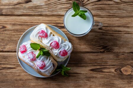 Kefir is decorated with a leaf of mint, a fermented drink. Air cake on a saucer. wood background