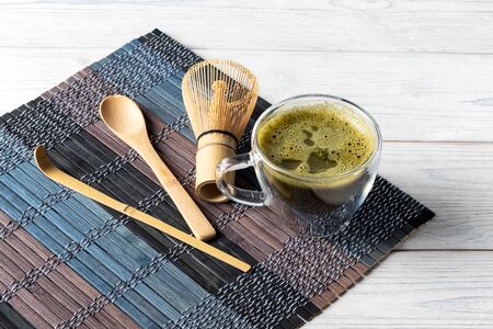 Green matcha tea drink and accessories on a white wooden background. Japanese tea ceremony concept.