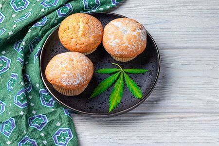 Cannabis and cupcakes with marijuana on a black plate, concept of medical marijuana, home cooking. View from aboveの写真素材