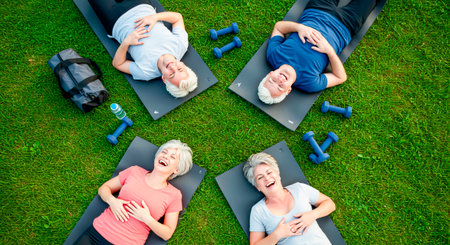 Post-workout break: A group of 50+ laughing on mats in the parkの素材