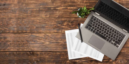 Notebook, paper with a table and pen on vintage wooden background. Workplace, work at home, freelance, students. Flat lay with copy space.の写真素材