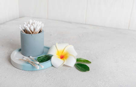 clean wooden and cotton ear buds environmental recyclable in the bathroom on a concrete background with a plumeria flower. Used in personal care, hygiene and makeup. Nobodyの写真素材