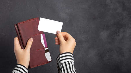 Mockup. A female hand holds a burgundy leather wallet with credit cards and takes out a blank...