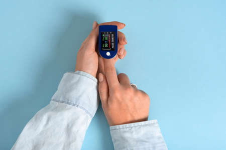 Female hands measure the pulse with a compact electronic pulse oximeter. Oxygen saturation, heart rate, pulse, blood oxygen level during coronavirus, other viral diseases, diabetes. Top view, flat layの写真素材