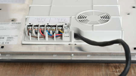 Electrical connection of the induction panel cooker, contacts, electricity. Pofessional wiring and installation hob in the kitchen.の写真素材