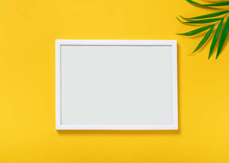 empty mock up photo frame on yellow background, tropical palm leaves. Summer travel concept,...