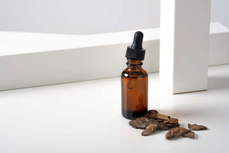 Mockup cosmetic face serum, oil brown glass bottle with a pipette on a stylish minimalist white background with geometric and tree bark, wood, sandalwood decor. Female beauty concept, empty template.の写真素材