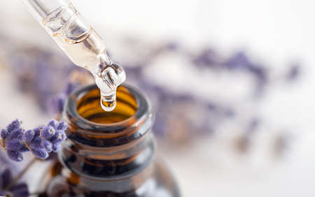Essential oil with a dropper pipette and lavender branches on a white background with copy space. Brown glass cosmetic bottle, serum.の写真素材