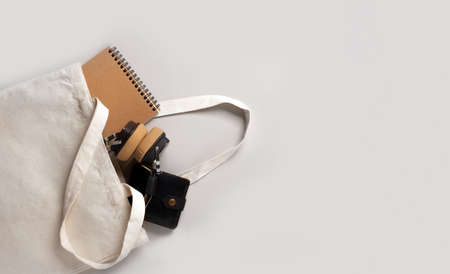 Mockup empty template White cream shopping bag for your design, eco friendly, zero waste with copy space. Minimalism flat lay. Inside there are headphones, a notebook and a men's wallet.の写真素材
