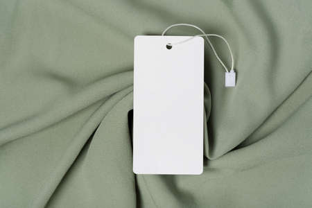 White clothing tag, label blank mockup template with the ribbon, to place your design. On a premium cotton green khaki fabric textile background.の写真素材