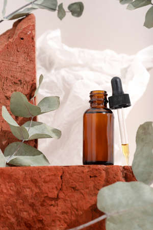 Mockup brown glass bottle with dropper serum on red stone and beige background with crumpled paper. Brutal. Copy space. Acid peeling, face oil, collagen.の写真素材