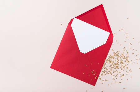 Blank square paper mockup envelope red, golden stars confetti on beige background. Flat lay, top view, copy space, minimalist. Christmas and New Year conceptの写真素材