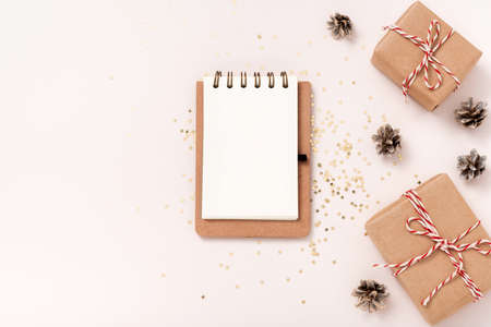 Notebook blank paper mockup, golden stars confetti, gift boxes on beige background. Flat lay, top view, copy space, minimalist. Christmas New year composition.の写真素材