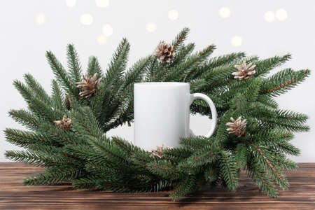 Christmas mockup one white empty tea mugs on a brown wooden table and branches of a Christmas tree wreath. Cup template for your design, logo with copy space. New Yearの写真素材
