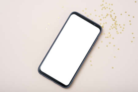 Modern smartphone with mockup on beige background with christmas decoration. Flat lay template....
