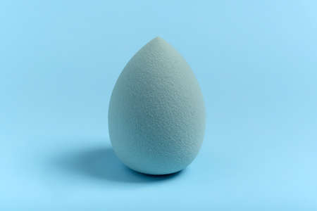 Blue cosmetic makeup sponge on a minimal background. Egg shape. Tool for applying foundation cream. Nobody.の写真素材