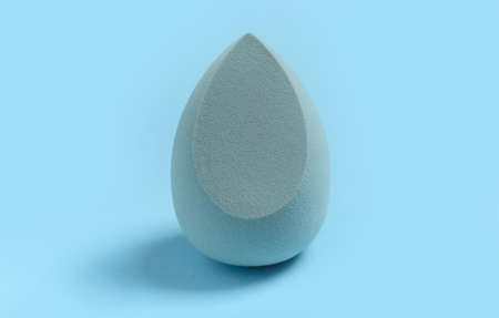 Blue cosmetic makeup sponge on a minimal background. Egg shape. Tool for applying foundation cream. Nobody.の写真素材