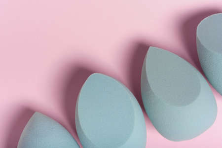 Blue cosmetic makeup sponge on a minimal pink background. A set of sponges of different shapes. Tool for applying foundation cream. Nobody.の写真素材