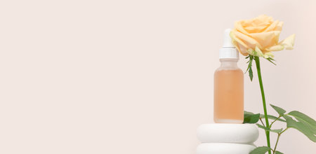 Mockup cosmetics serum with a pipette in a transparent frosted glass and orange liquid. Facial peeling with lactic Aha acid on a white pedestal, beige background with rosesの写真素材