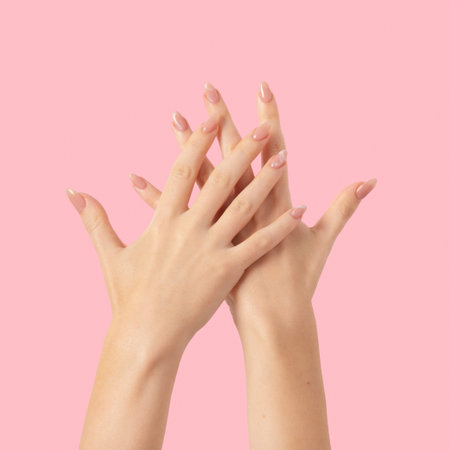 Hands of a beautiful well-groomed with feminine beige marble design nails gel polish on a pink background. Manicure, pedicure beauty salon concept.の写真素材