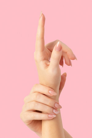 Hands of a beautiful well-groomed with feminine beige nude marble design nails gel polish on a pink background. Manicure, pedicure beauty salon concept.の写真素材