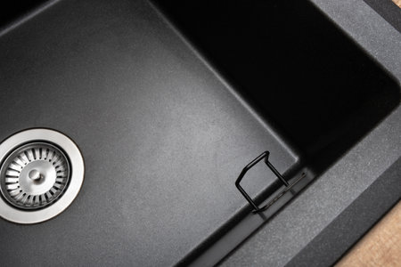 Organizer holder for a kitchen sponge in a black, clean granite sink. Storage and organization of space, details in the kitchenの写真素材