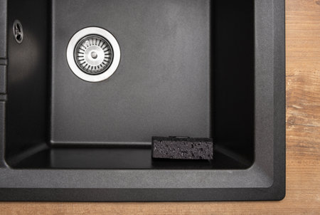 Organizer holder for a kitchen sponge in a black, clean granite sink, strainer. Storage and organization of space, details in the kitchenの写真素材