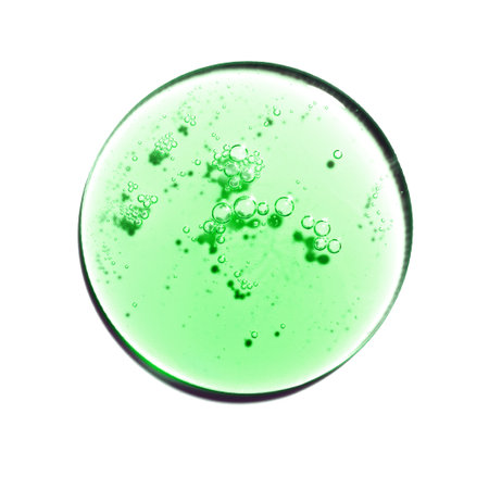 Texture swatch of green gel or oil on white isolated background, macro. Detergent, cosmetics, laboratory. A round drop in a petri dishの写真素材