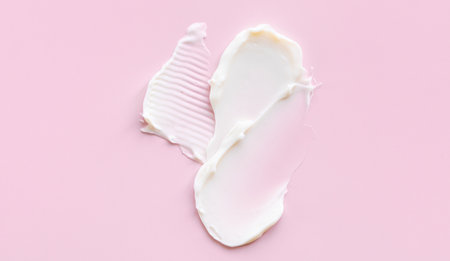 Swatch of white cream texture, cosmetics for face and body on a isolated light pink background. Smear.の写真素材