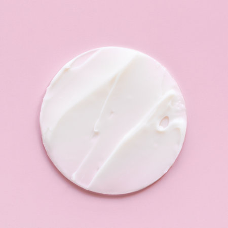 Swatch of white cream texture, cosmetics for face and body on a isolated light pink background. Smear roundの写真素材