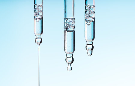 ??? pipette serum drop with clear liquid niacinamide, hyaluronic or Aha Bha acids on a blue white isolated background. Textured swatch skincare. Laboratory cosmeticsの写真素材
