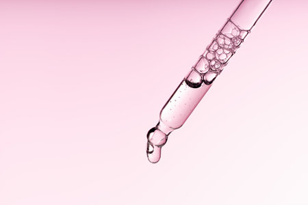 Pipette serum with clear liquid niacinamide, hyaluronic or Aha Bha acids on a pink white isolated background. Textured swatch skincare. Laboratory cosmeticの写真素材