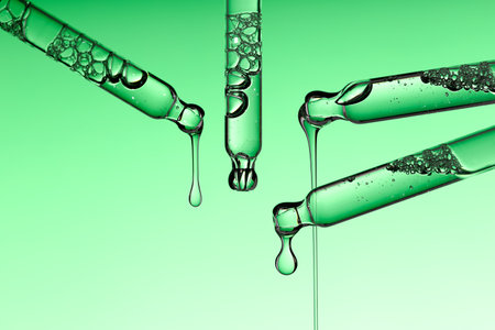Set pipette serum drop with clear liquid niacinamide, hyaluronic or Aha Bha acids on a green isolated background. Textured swatch skincare. Laboratory cosmeticsの写真素材