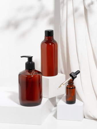 A set of care cosmetics for the body, bathing. Mockup template of brown dispenser bottles of shower gel or liquid soap, cream and body massage oil on white background with geometriの写真素材