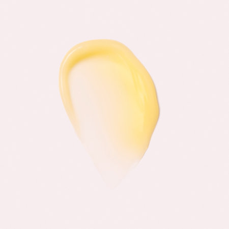 Swatch of yellow cream texture retinol, cosmetics for face and body on a isolated beige background. Drop smear. Real photoの写真素材