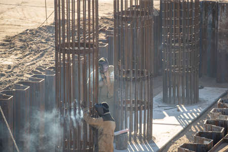 Welders in protective masks are engaged in welding work, in the open air, outside of an industrial enterprise. Harm to the health of the welder will cause inhalation of smoke when welding steel.の写真素材