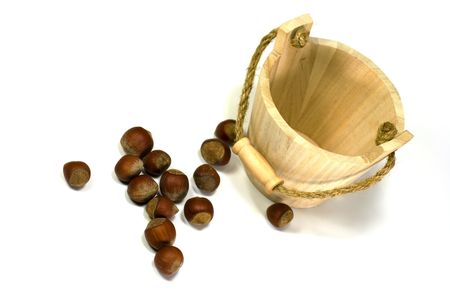 hazelnuts and empty wooden busket on white backgroundの写真素材