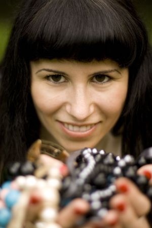 closeup portrait on young brunette holding a lot of beadsの写真素材