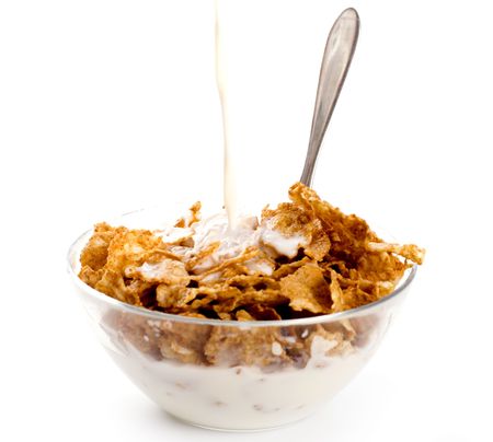 milk pouring onto cornflakes isolated on white