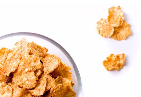 cornflakes in glass bowl on white background