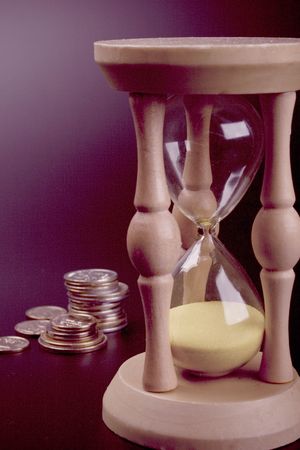 sand clock and coins on black background