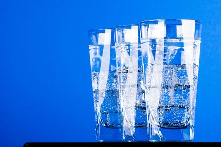 three glasses with cold water on blue backgroundの写真素材