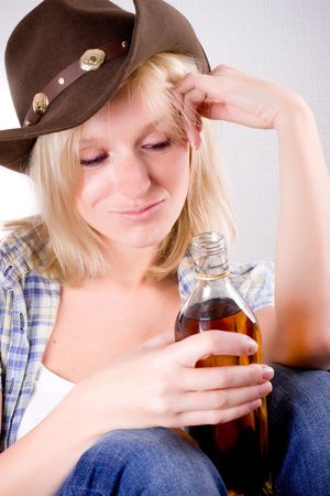 pretty western woman in cowboy shirt and hat with bottle of whiskeyの写真素材
